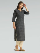 Woman wearing a black patterned kurta with beige pants and a round neckline on a grey background