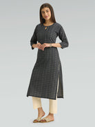 Woman wearing a dark gray patterned kurta with white pants on a light gray background