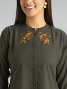 Woman wearing a dark green kurta with floral embroidery on a plain background