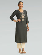 Woman wearing a dark gray kurta with intricate embroidery on a light gray background