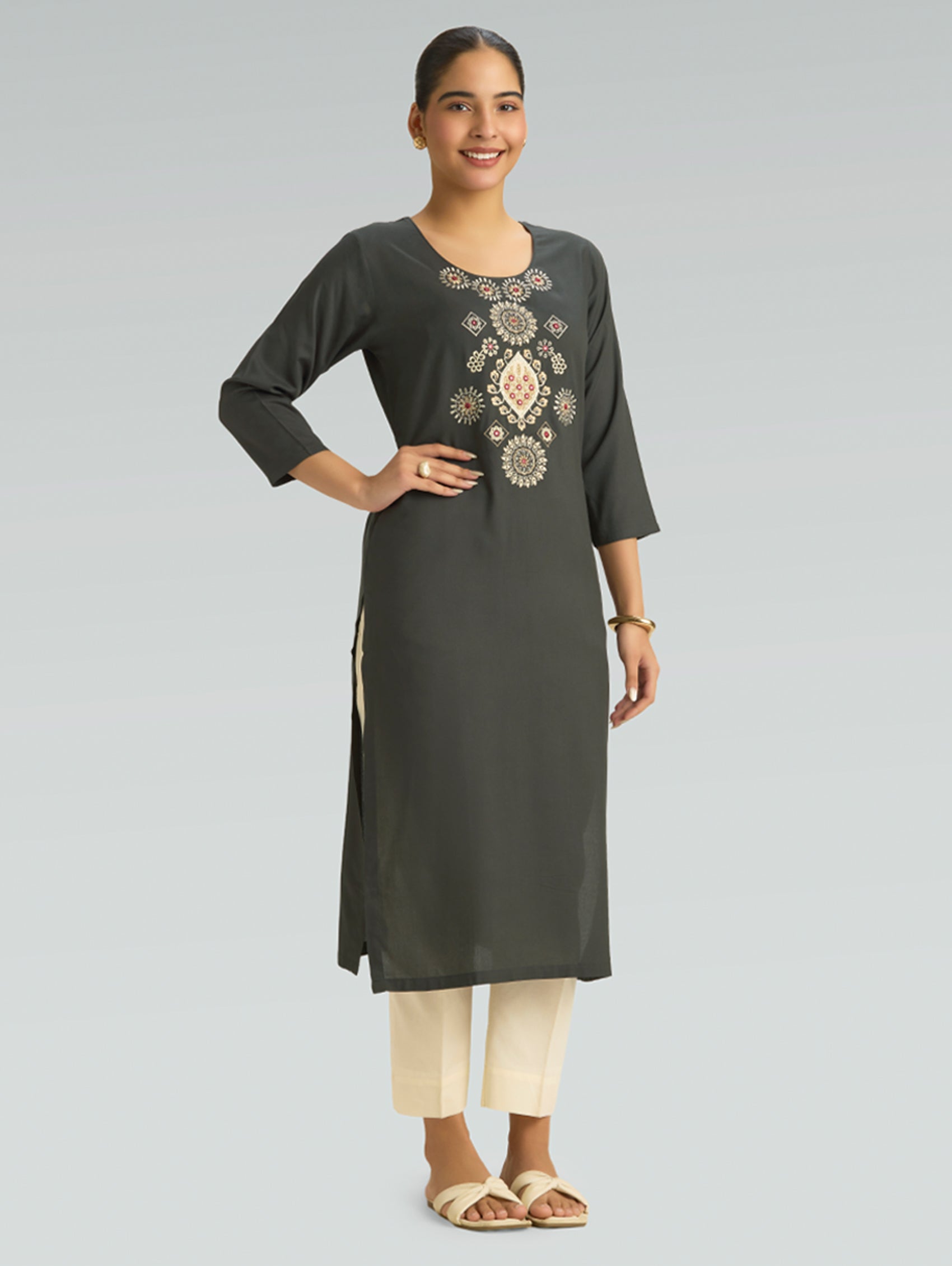 Woman wearing a dark gray kurta with intricate embroidery on a light gray background