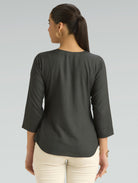Woman wearing a dark gray top with 3/4 sleeves on a light gray background