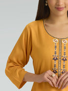 Mustard yellow kurta with floral embroidery on a plain background
