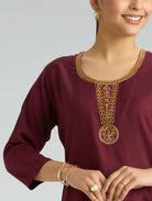 Maroon top with gold embroidery on a plain background
