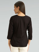 Woman wearing a black top with 3/4 sleeves on a gray background