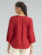 Woman wearing a red top with a plain background