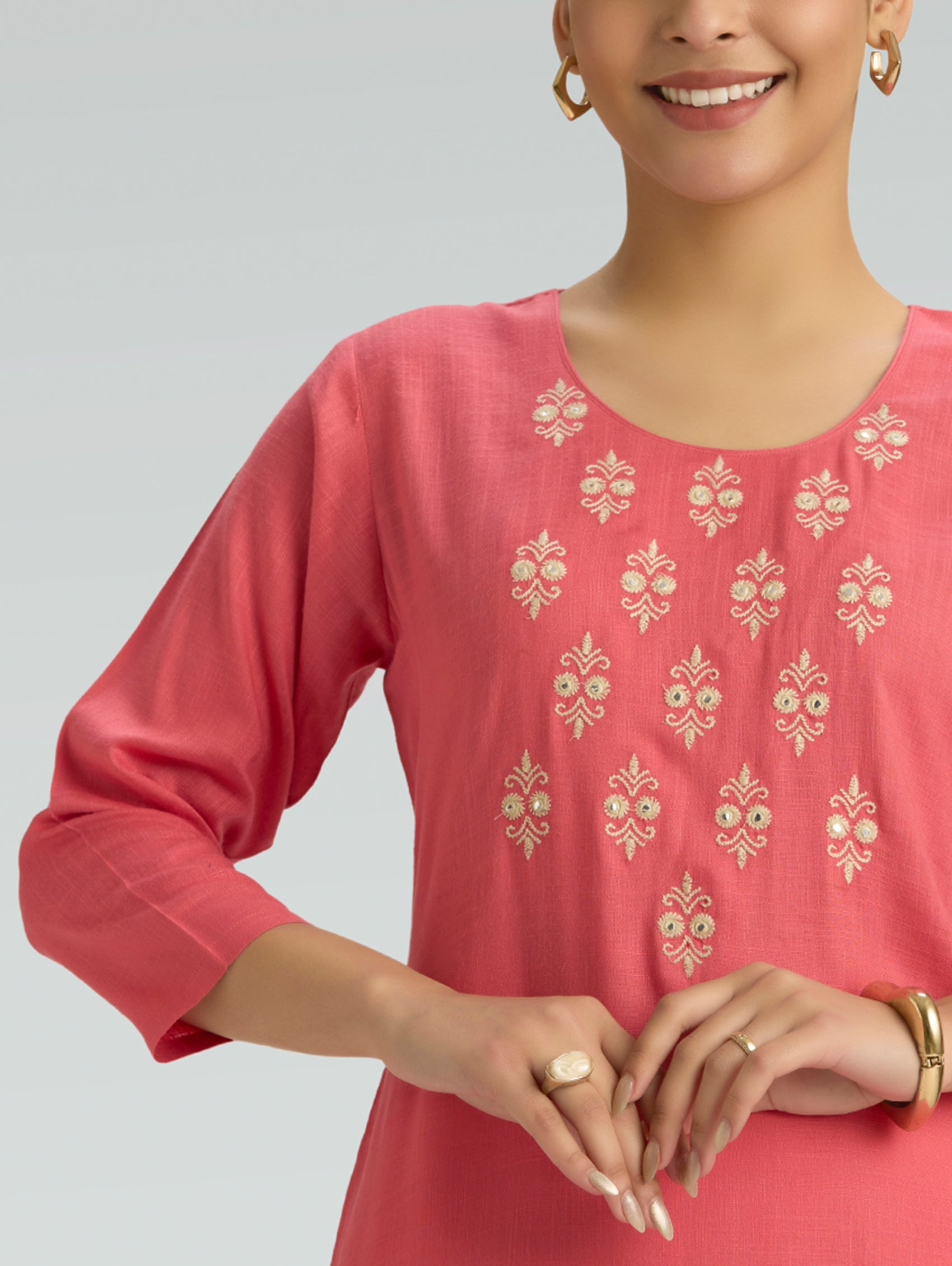 Woman wearing a Red embroidered top against a grey background