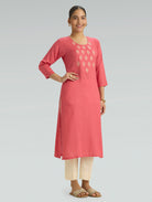 Woman wearing a pink kurta with embroidery on a gray background