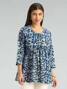 Woman wearing a blue floral patterned blouse on a gray background