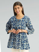 Woman wearing a blue patterned blouse against a gray background