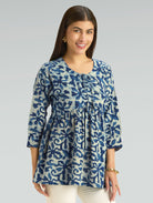 Woman wearing a blue patterned blouse against a gray background