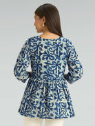Woman wearing a blue and white patterned dress against a gray background