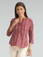 Woman wearing a patterned maroon top against a gray background
