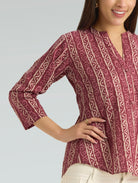 Woman wearing a patterned blouse with a plain background