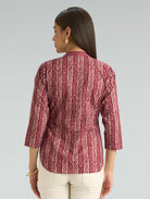 Woman wearing a red patterned blouse against a gray background