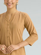 Woman wearing a brown patterned top against a light gray background