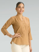 Woman wearing a beige blouse with a plain background