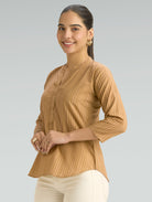 Woman wearing a brown textured top against a gray background