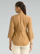 Woman wearing a brown striped shirt against a gray background