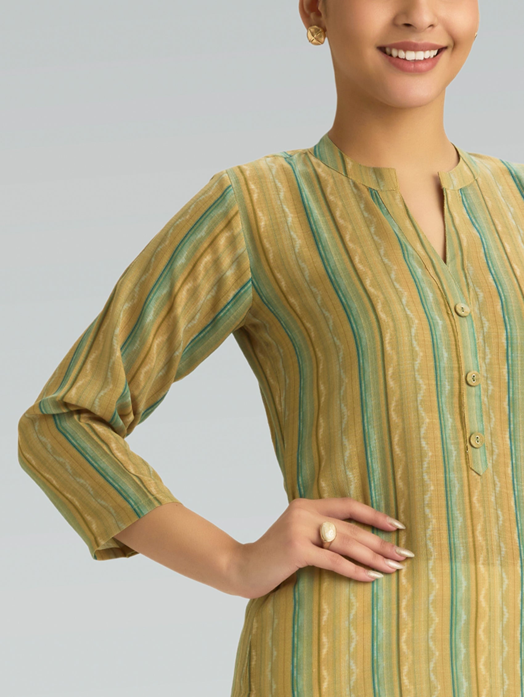 Woman wearing a yellow and green striped kurta against a gray background