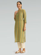 Woman wearing a green and beige striped kurta with white pants on a gray background