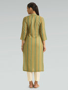 Woman wearing a green and beige striped kurta with white pants on a gray background