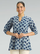 Woman wearing a blue and white patterned top on a gray background
