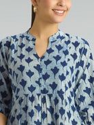 Woman wearing a blue and white patterned dress against a gray background