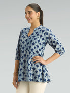 Woman wearing a blue patterned top on a gray background