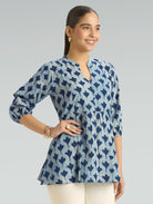 Woman wearing a blue patterned blouse on a gray background