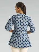 Woman wearing a blue and white patterned shirt against a gray background