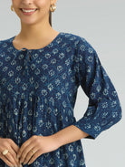 Woman wearing a blue patterned dress on a gray background