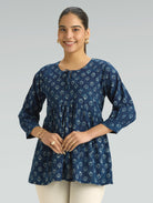 Woman wearing a blue floral patterned top against a gray background
