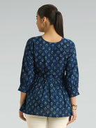 Woman wearing a blue patterned top on a gray background