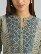 Close-up of a person wearing a traditional outfit with intricate embroidery on a plain background