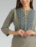 Woman wearing a patterned green kurta with a plain background