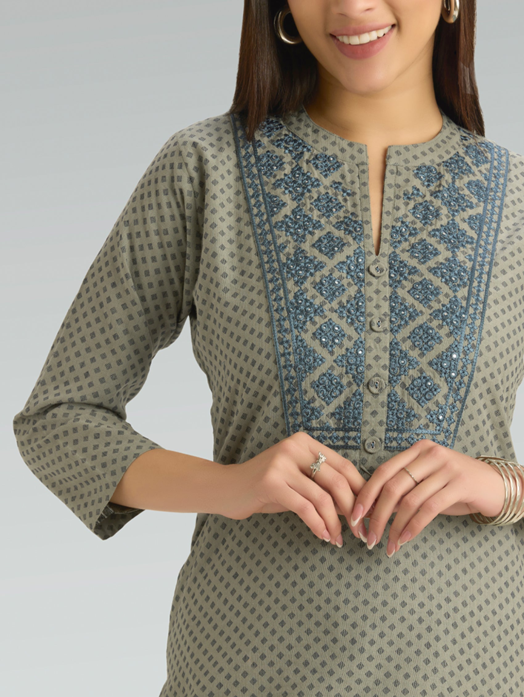 Woman wearing a patterned green kurta with a plain background