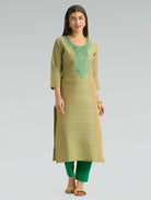 Woman wearing a green kurta with embroidery on a gray background
