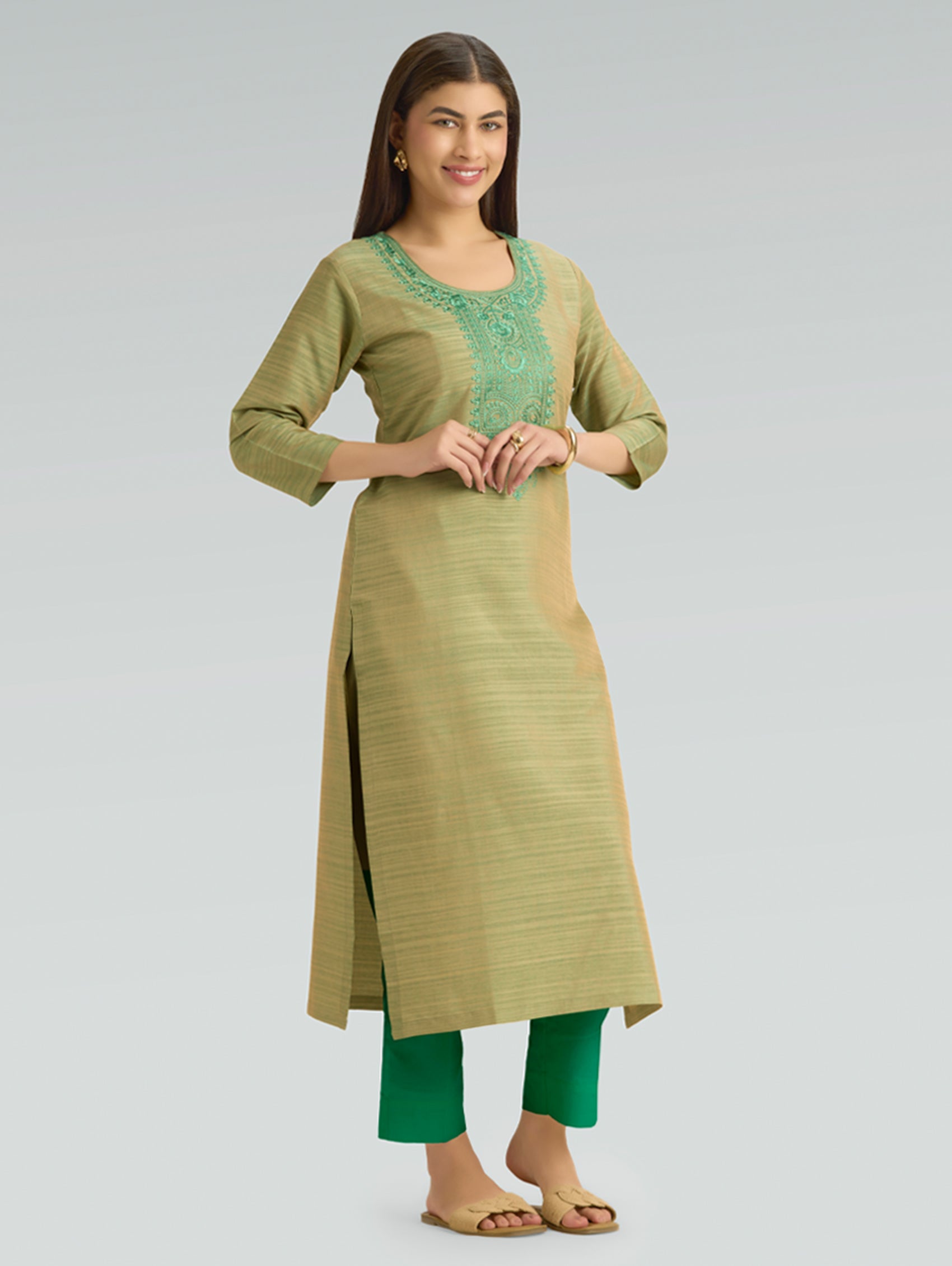 Woman wearing a green and beige traditional outfit on a gray background