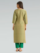 Woman wearing a green kurta with green pants on a light gray background