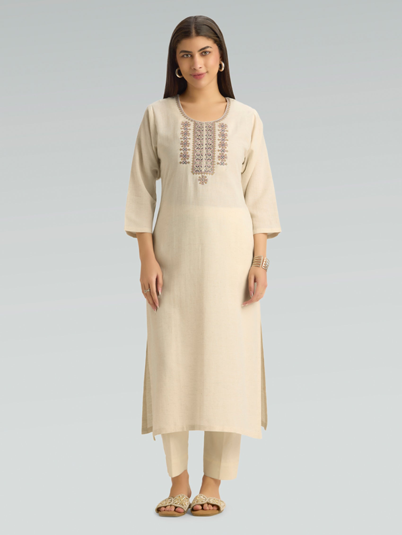 Woman wearing a beige kurta with embroidery on a light gray background