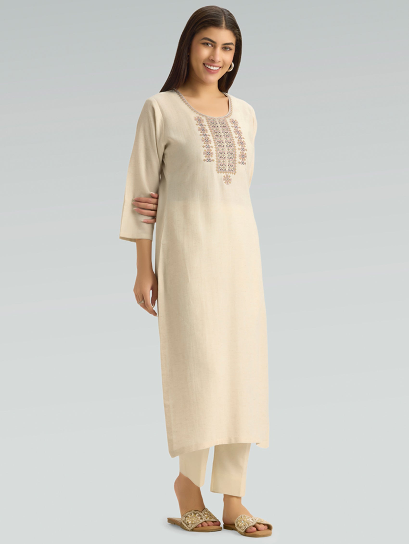 Woman wearing a beige kurta with embroidery on a gray background
