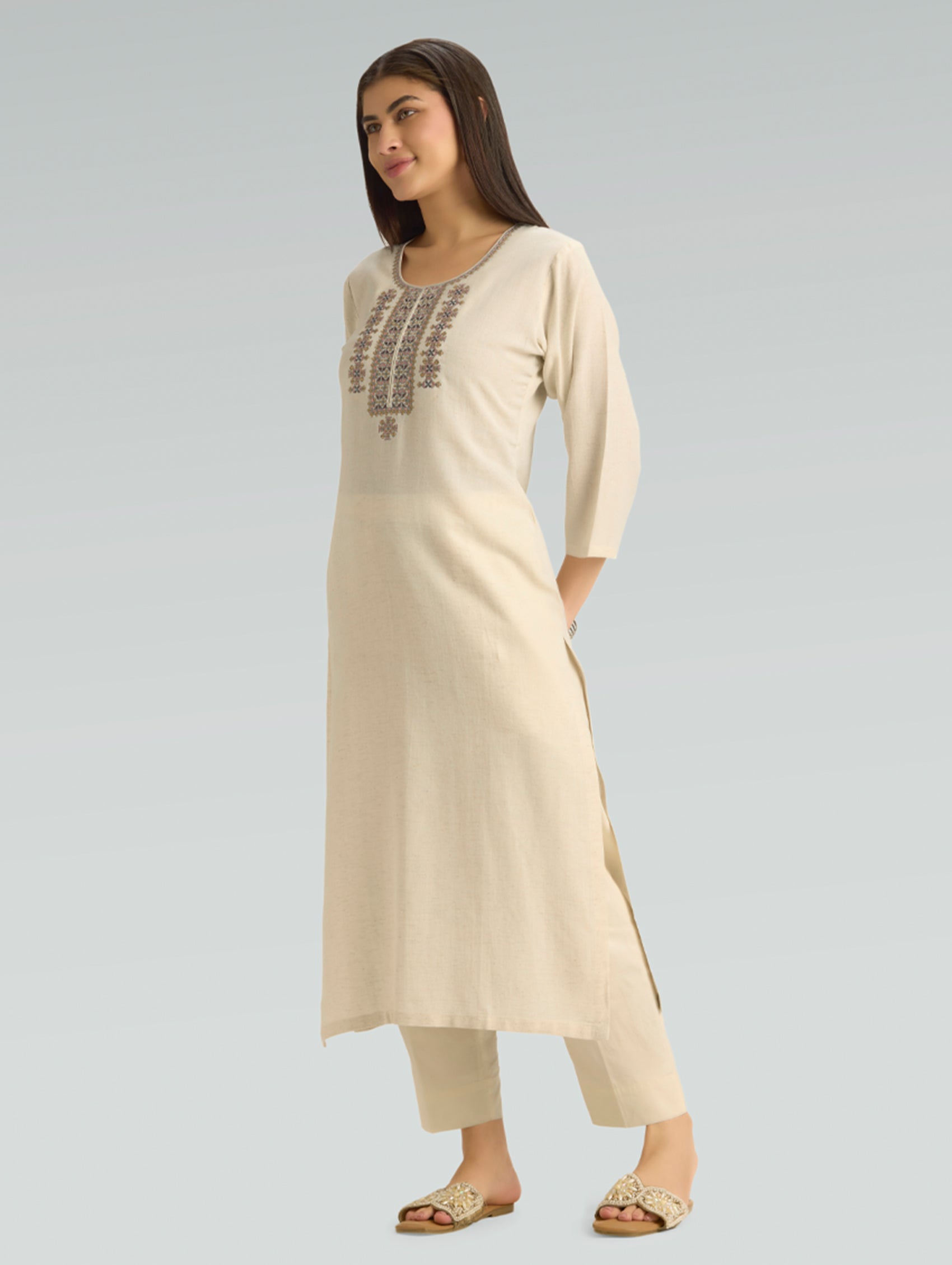 Woman wearing a beige kurta with embroidery on a light gray background