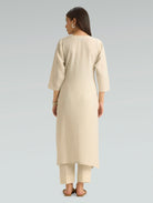 Woman wearing a beige kurta with pants on a gray background