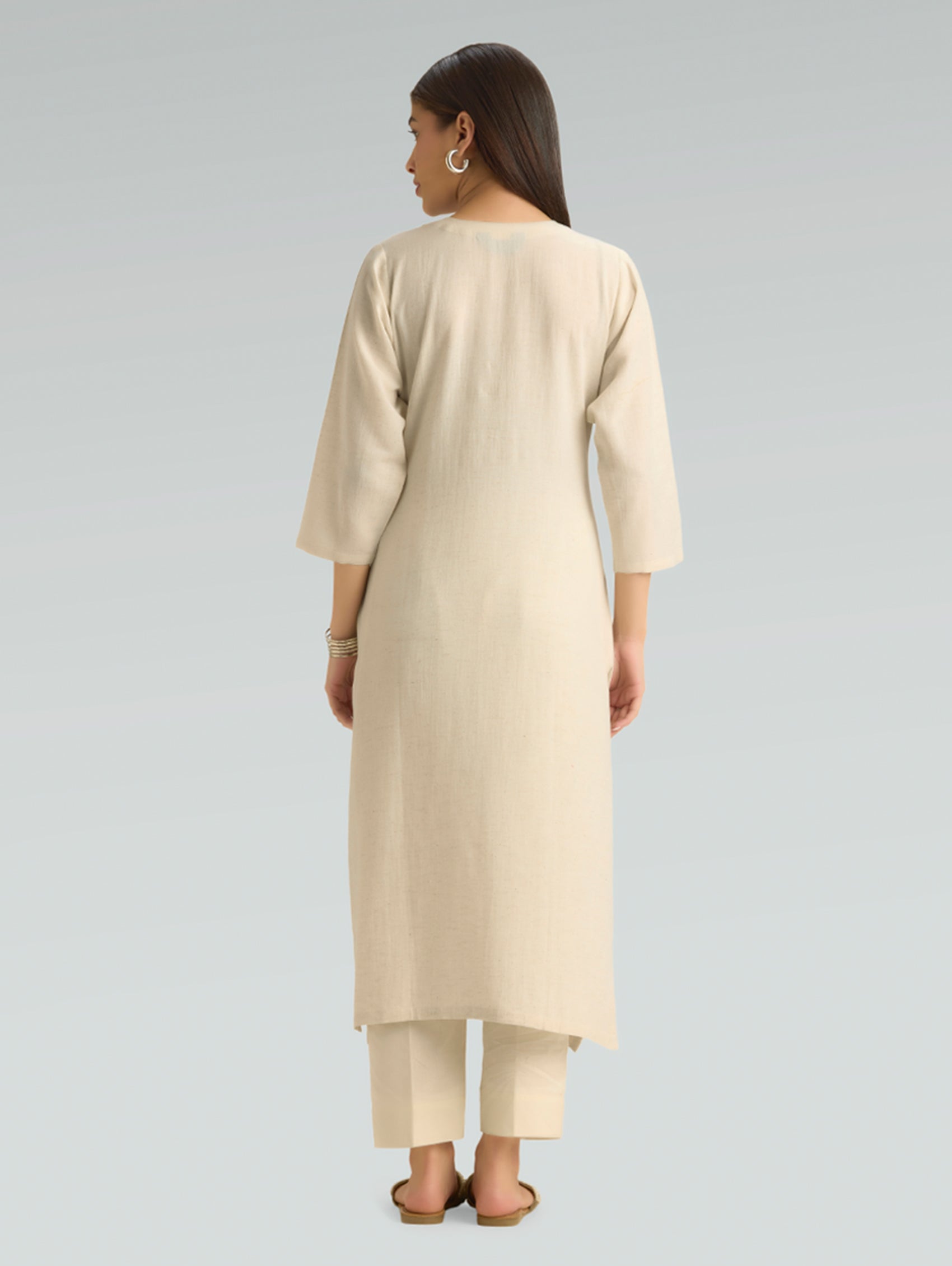 Woman wearing a beige kurta with pants on a gray background