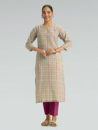 Woman wearing a patterned kurta with pink pants on a gray background