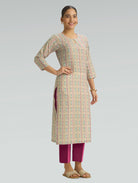 Woman wearing a patterned kurta with maroon pants on a light gray background