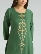 Green dress with gold embroidery on a plain background
