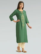 Woman wearing a green kurta with gold embroidery on a gray background