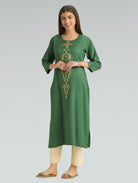 Woman wearing a green embroidered kurta with beige pants on a gray background